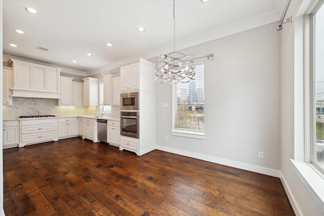 kitchen featuring pendant lighting, tasteful backsplash, white cabinetry, stainless steel appliances, and crown molding