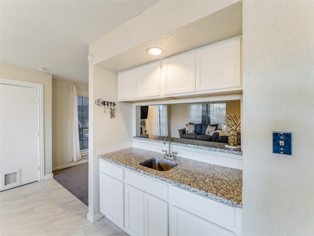 kitchen featuring light stone countertops, sink, and white cabinets