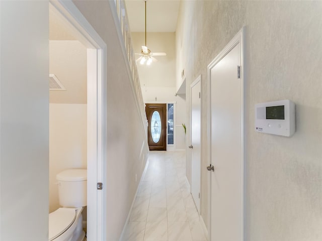 corridor featuring light tile patterned floors and a high ceiling