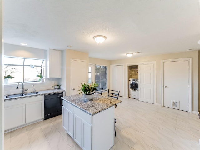 kitchen with white cabinetry, washer / dryer, black dishwasher, sink, and a center island