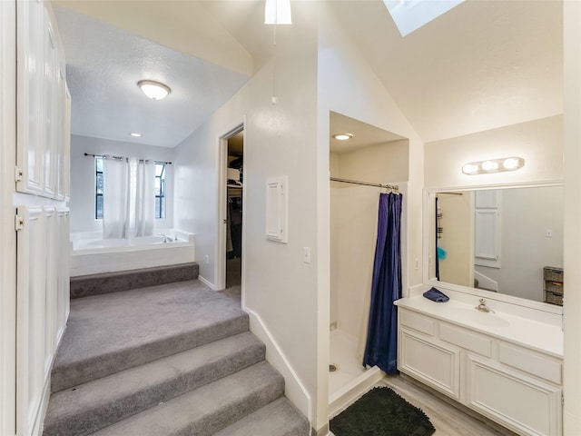 bathroom with lofted ceiling, vanity, and shower with separate bathtub