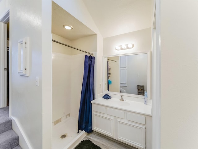 bathroom featuring vaulted ceiling, wood-type flooring, vanity, and walk in shower