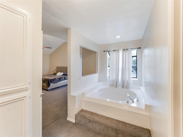 bathroom featuring tiled tub, vaulted ceiling, and a textured ceiling