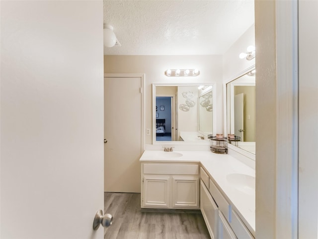 bathroom featuring wood-type flooring, vanity, and a textured ceiling