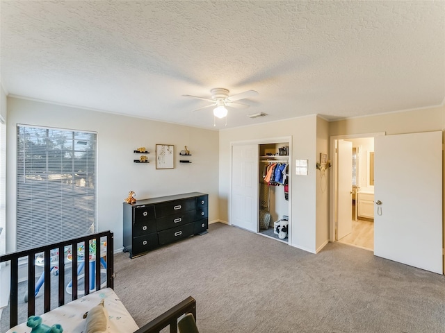 carpeted bedroom with ensuite bath, ceiling fan, a textured ceiling, a walk in closet, and a closet