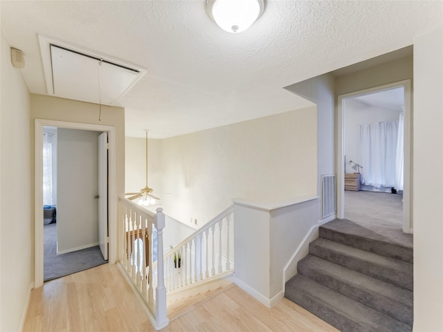 corridor with a textured ceiling and light hardwood / wood-style floors