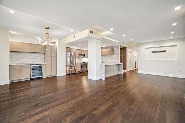 unfurnished living room with an inviting chandelier, dark hardwood / wood-style floors, and beverage cooler