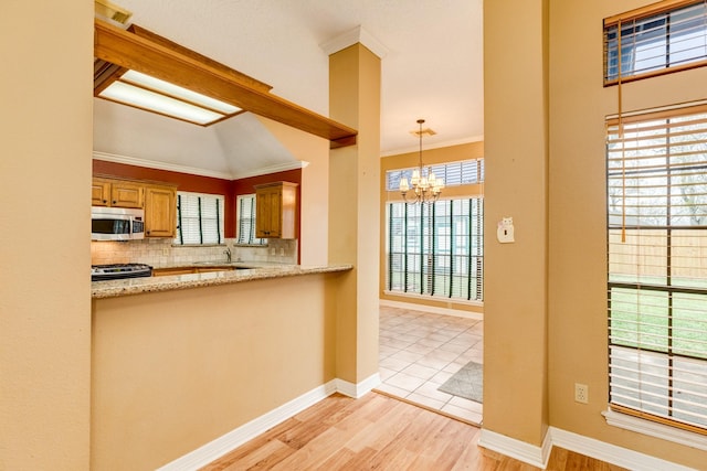 kitchen featuring tasteful backsplash, ornamental molding, stainless steel appliances, and decorative light fixtures