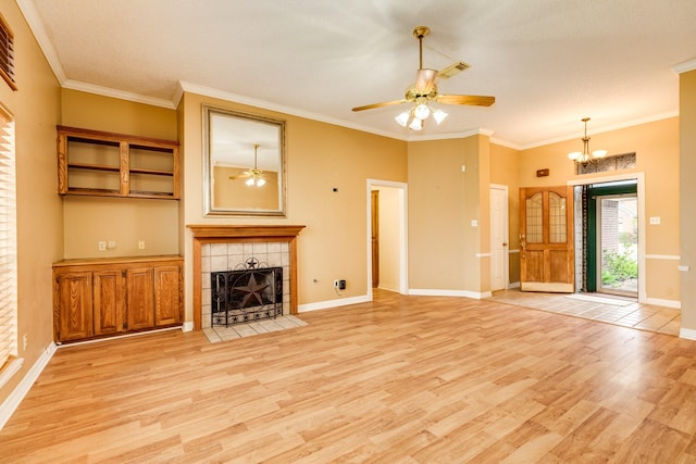 unfurnished living room featuring a tiled fireplace, crown molding, ceiling fan with notable chandelier, and light wood-type flooring