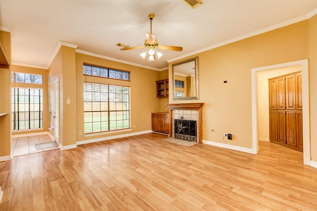 unfurnished living room with ornamental molding, a tile fireplace, ceiling fan, and light wood-type flooring