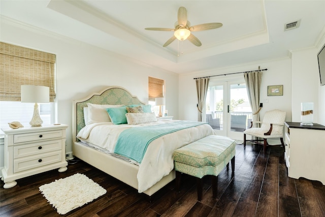 bedroom featuring dark wood-type flooring, ceiling fan, access to exterior, a tray ceiling, and ornamental molding