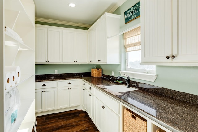 kitchen with white cabinetry, sink, dark stone countertops, and ornamental molding