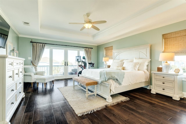 bedroom featuring ceiling fan, dark hardwood / wood-style floors, a raised ceiling, and access to outside