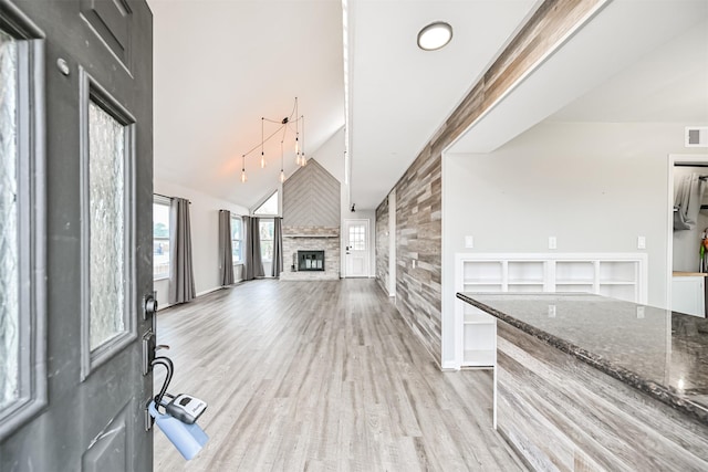 unfurnished living room featuring lofted ceiling, a fireplace, and light hardwood / wood-style floors