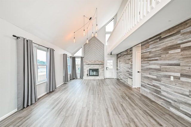 unfurnished living room featuring a fireplace, light wood-type flooring, and a high ceiling