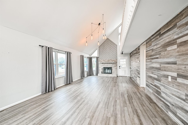 unfurnished living room with hardwood / wood-style flooring, a stone fireplace, and high vaulted ceiling