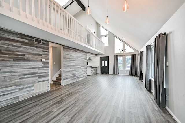 unfurnished living room featuring dark wood-type flooring, high vaulted ceiling, and beamed ceiling