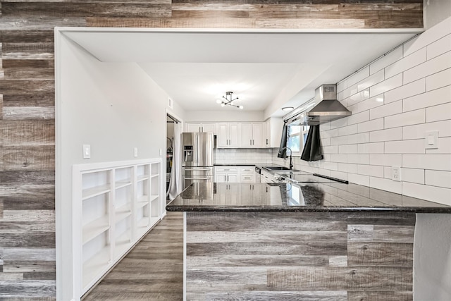 kitchen featuring tasteful backsplash, white cabinetry, sink, stainless steel fridge, and kitchen peninsula