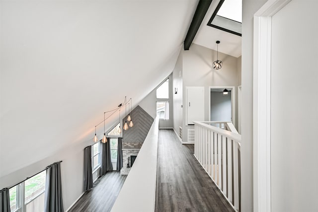 hall with beam ceiling, dark hardwood / wood-style flooring, high vaulted ceiling, and a wealth of natural light