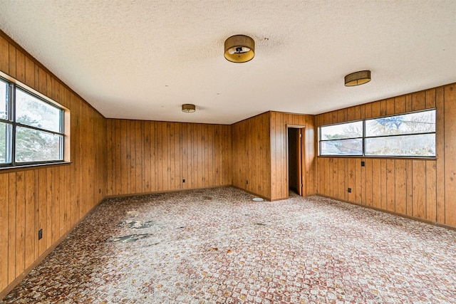 empty room featuring a textured ceiling and wood walls