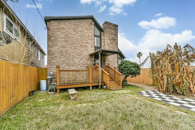 rear view of house featuring a wooden deck and a lawn