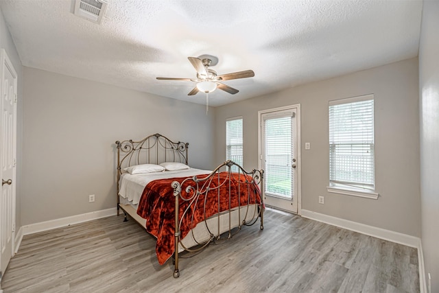 bedroom featuring access to exterior, a textured ceiling, light hardwood / wood-style floors, and ceiling fan