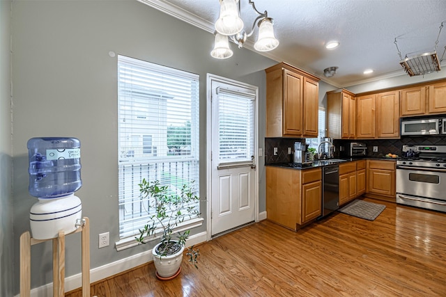 kitchen featuring sink, decorative light fixtures, light hardwood / wood-style flooring, appliances with stainless steel finishes, and backsplash