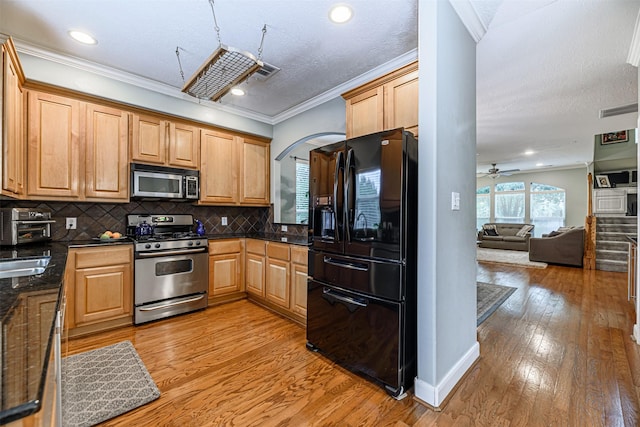 kitchen featuring backsplash, ornamental molding, ceiling fan, light hardwood / wood-style floors, and stainless steel appliances