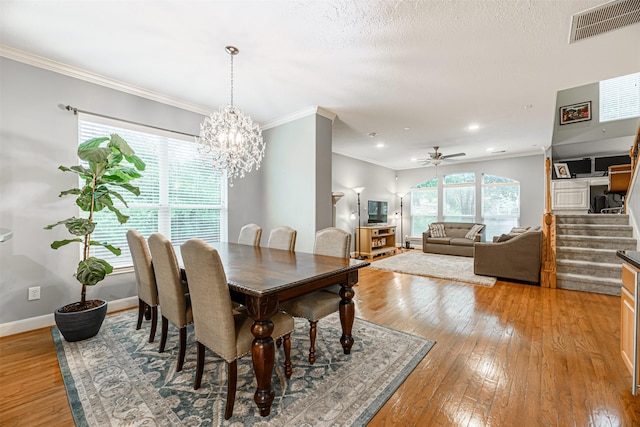 dining room featuring ornamental molding, ceiling fan with notable chandelier, a textured ceiling, and light wood-type flooring