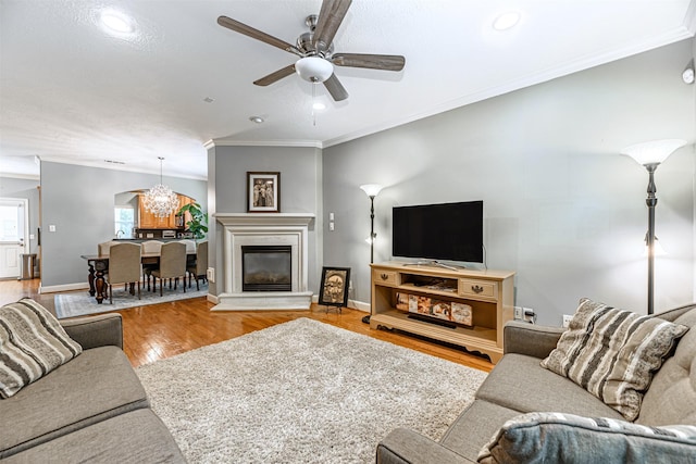 living room with hardwood / wood-style flooring, ceiling fan, and ornamental molding