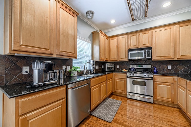 kitchen with sink, tasteful backsplash, light hardwood / wood-style flooring, dark stone countertops, and stainless steel appliances