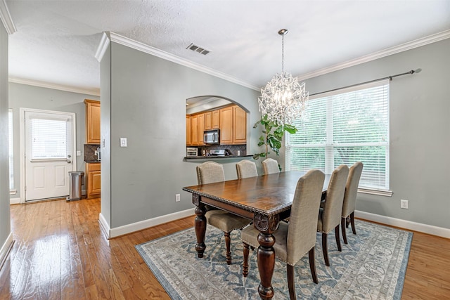 dining room featuring a notable chandelier, crown molding, light hardwood / wood-style flooring, and a textured ceiling