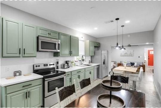 kitchen with appliances with stainless steel finishes, green cabinets, and decorative light fixtures