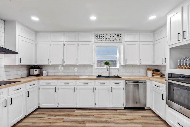 kitchen featuring appliances with stainless steel finishes, butcher block counters, sink, white cabinets, and light hardwood / wood-style flooring