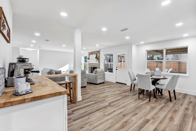 dining space with a brick fireplace and light hardwood / wood-style floors