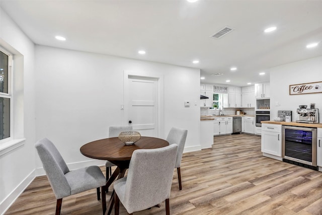 dining space featuring wine cooler, sink, and light hardwood / wood-style flooring