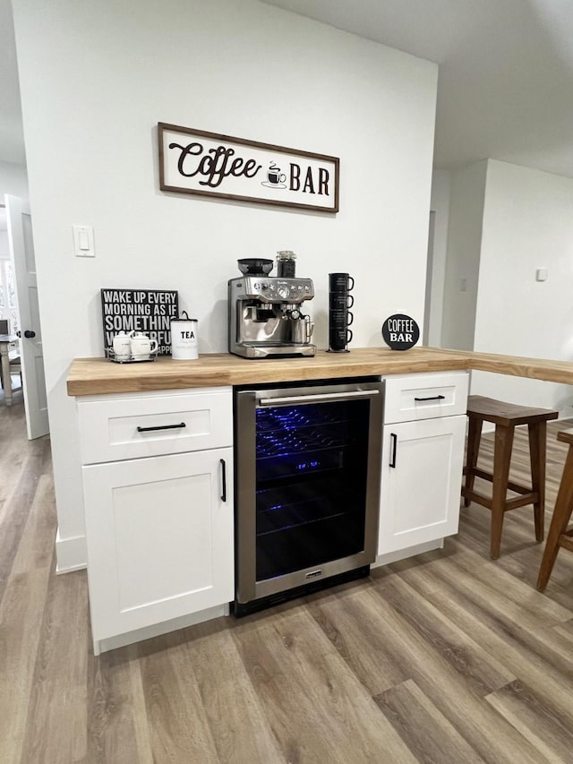 bar featuring wine cooler, butcher block countertops, white cabinetry, and light hardwood / wood-style flooring