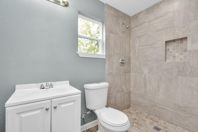 bathroom with vanity, tiled shower, and toilet