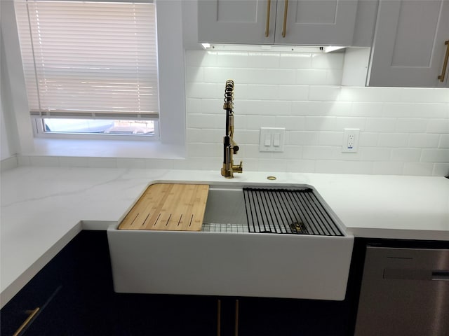 kitchen with backsplash, stainless steel dishwasher, sink, and white cabinets