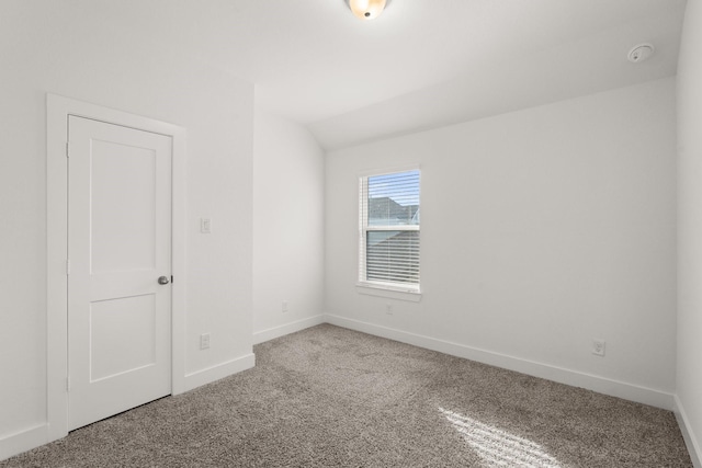 carpeted empty room featuring vaulted ceiling