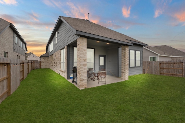 back house at dusk with a yard and a patio area