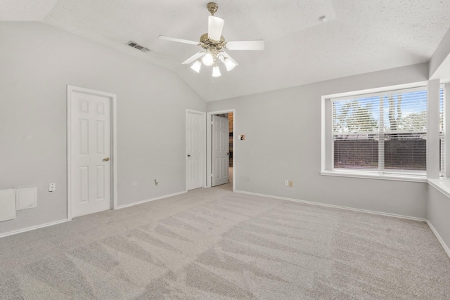 carpeted spare room featuring vaulted ceiling, a textured ceiling, and ceiling fan