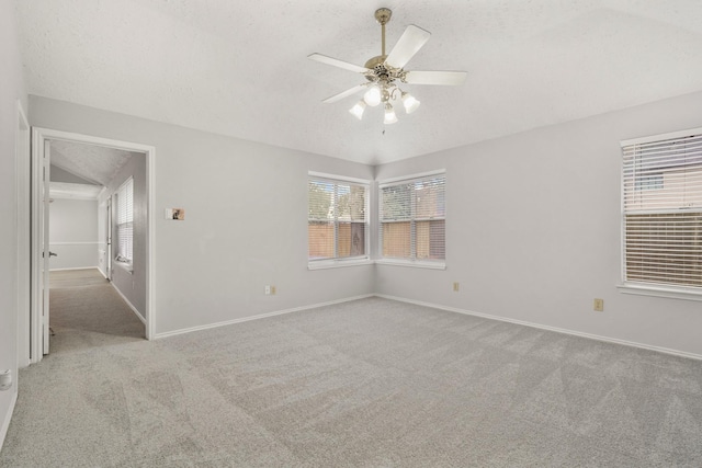 carpeted empty room with ceiling fan, lofted ceiling, and a textured ceiling