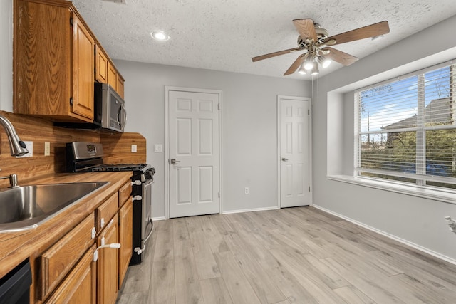 kitchen featuring appliances with stainless steel finishes, a textured ceiling, and light wood-type flooring