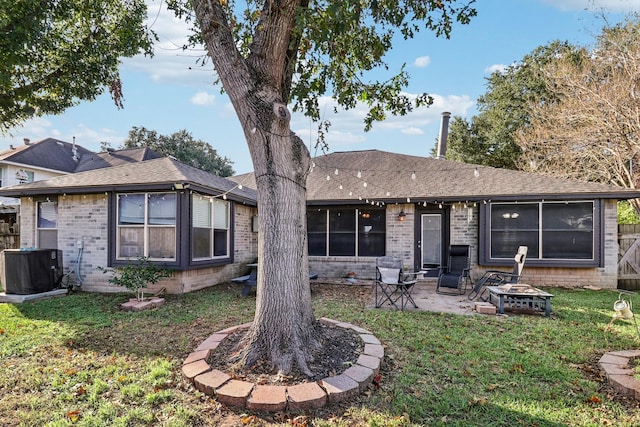 rear view of house with a patio, a yard, central air condition unit, and a fire pit