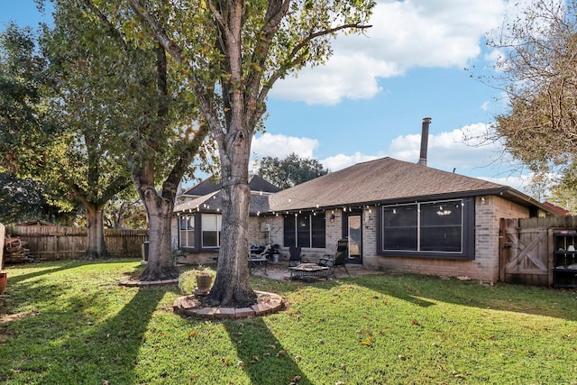 rear view of house with a lawn and an outdoor fire pit