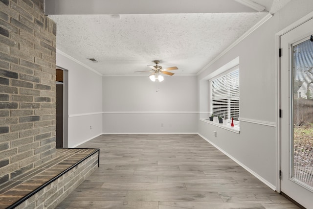 unfurnished room featuring ceiling fan, crown molding, a textured ceiling, and light wood-type flooring