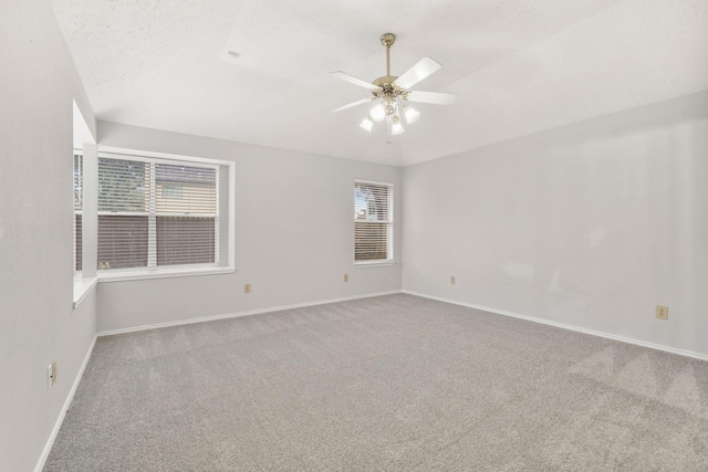 carpeted spare room with ceiling fan, a healthy amount of sunlight, and a textured ceiling