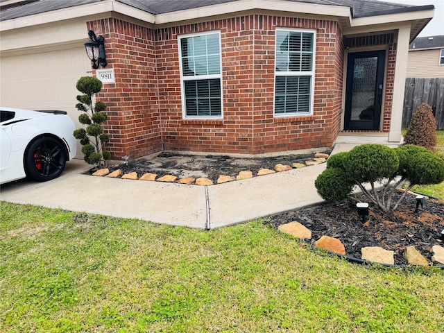 view of exterior entry featuring a garage and a yard