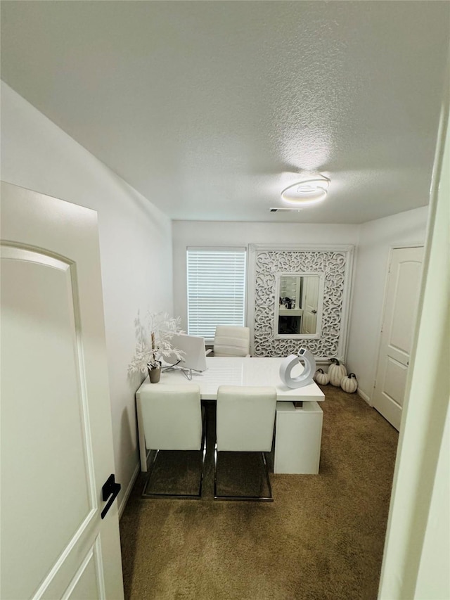 bedroom featuring a textured ceiling and dark carpet